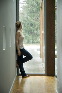 Frau in einer Halle schaut aus dem Fenster - NHF00445