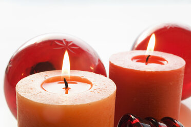 Christmas decoration with burning candle and christmas baubles, close-up - MSF01998