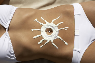 Frau mit sonnenförmiger Sonnencreme auf dem Bauch - WESTF05127