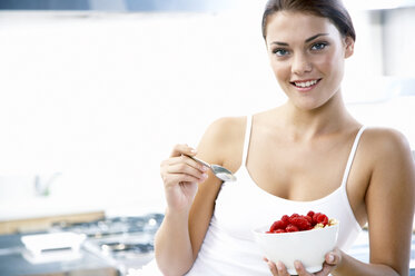 Young woman holding bowl with rasberries - WESTF05049