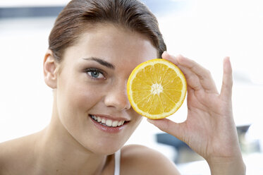 Young woman holding sliced orange - WESTF05043