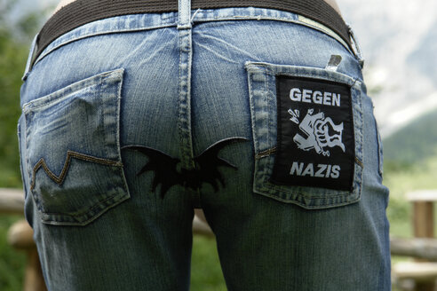 Rückenansicht einer Frau in Jeans mit Anti-Nazi-Applikation - GNF00905