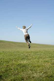 Woman jumping in meadow, rear view - GNF00915