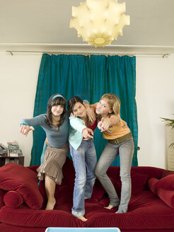 Mädchen tanzen auf dem Sofa - KMF00945