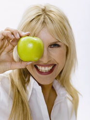 Woman holding green apple, portrait - WESTF05416