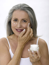 Ältere Frau trägt Gesichtscreme auf, Porträt - WESTF05346