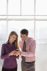 Business man and woman looking at mobile phone - WESTF05587