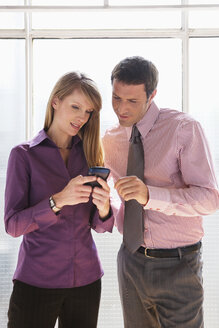 Business man and woman looking at mobile phone - WESTF05586