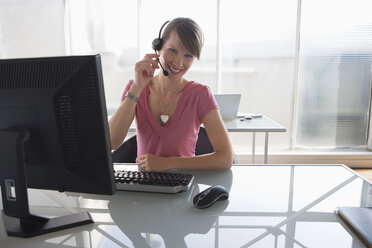 Frau arbeitet am Computer und trägt ein Headset - WESTF05548