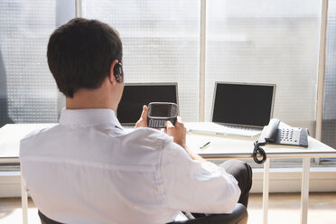 Business man using headset and mobile phone, rear view - WESTF05527