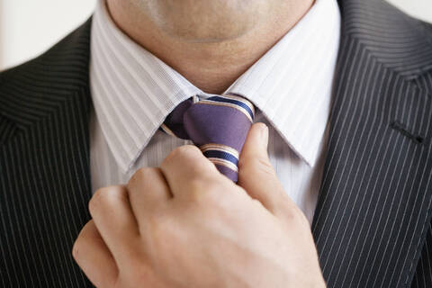 Geschäftsmann passt Krawatte an, Nahaufnahme, lizenzfreies Stockfoto