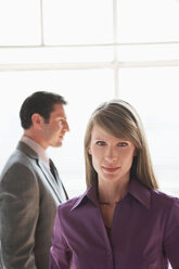 Portrait of business woman, male colleague in background - WESTF05502