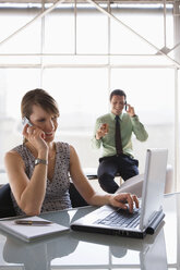 Teamwork in business, woman using laptop while phoning - WESTF05484