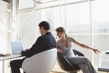 Business man working on laptop, female colleague with headset - WESTF05474