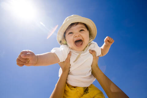 Hände halten Baby (6-9 Monate) in die Luft, Porträt, lizenzfreies Stockfoto