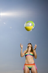 Junge Frau im Bikini, die einen Strandball wirft - CLF00416