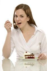 Young woman eating piece of cake, portrait - CLF00388
