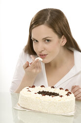 Young woman nibbling cake, portrait - CLF00384