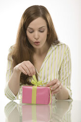 Junge Frau öffnet rosa Geschenk, Porträt - CLF00376