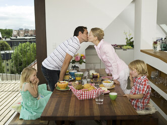 Family at breakfast table, parents kissing - WESTF05902