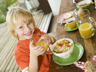 Boy at breakfast table, holding glass of juice - WESTF05897