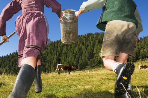 Couple running, holding milk can, rear view - HHF01505