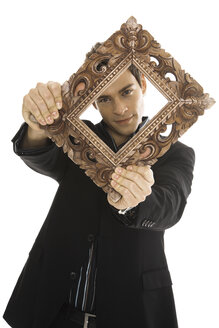 Young man holding picture frame, close-up - PKF00172