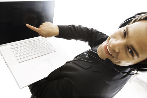 Young man wearing head set, holding laptop, close-up - PKF00140