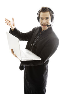 Young man wearing headphones, holding laptop,close-up - PKF00138