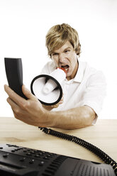 Mann hält Telefon in der Hand und schreit in ein Megaphon - PKF00095