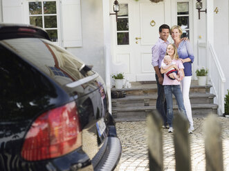 Family with baby standing in front of house - WESTF06146