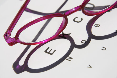 Two pair of glasses kept on an eye chart, close-up - TL00210