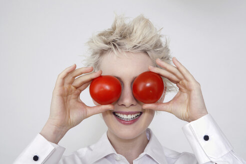 Junge Frau hält sich Tomaten vor die Augen, Porträt - TCF00210