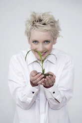 Junge Frau hält eine Pflanze, Porträt - TCF00200