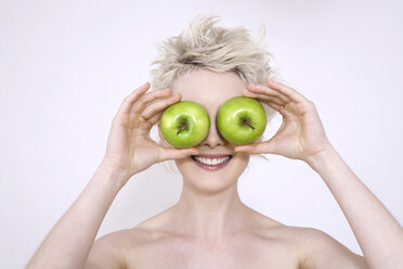 Junge Frau hält Äpfel über die Augen, Porträt - TCF00192