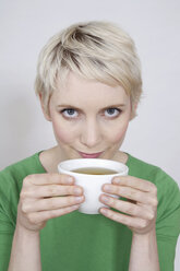 Young woman holding tea bowl, portrait - TCF00165