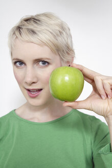 Junge Frau, die einen grünen Apfel hält, Porträt - TCF00162