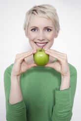 Junge Frau, die einen grünen Apfel hält, Porträt - TCF00161