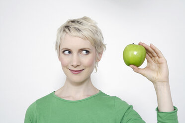 Junge Frau, die einen grünen Apfel hält, Porträt - TCF00156