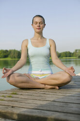 Frau (20-25) übt Yoga auf dem Steg - CKF00150