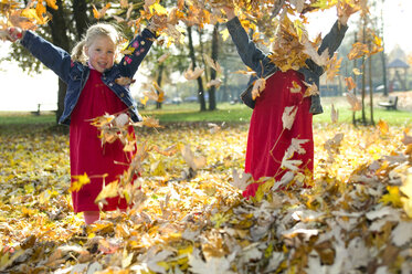 Twins playing with autumn leaves, close-up - CKF00135