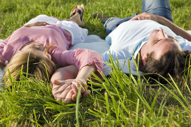 Couple lying in meadow, hand in hand - LDF00553