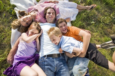 Young family lying in field, embracing, elevated view - LDF00551