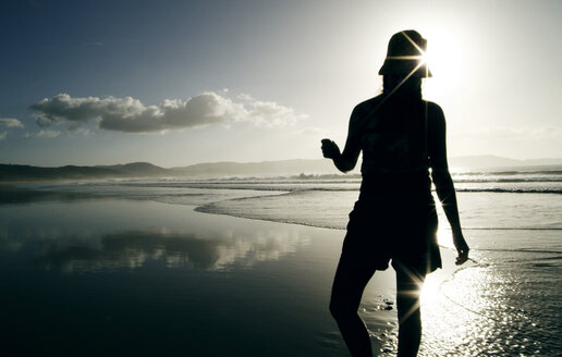 New Zealand, woman standing on beach, rear view - PKF00237