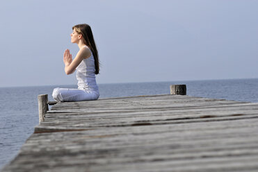 Italy, Lake Garda, Young woman (20-25) exercising yoga - DKF00115
