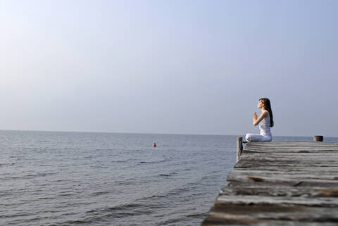 Italy, Lake Garda, Young woman (20-25) exercising yoga, lizenzfreies Stockfoto