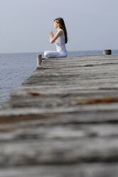 Italy, Lake Garda, Woman (20-25) exercising yoga on jetty - DKF00113