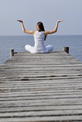 Italy, Lake Garda, Woman (20-25) exercising yoga on jetty - DKF00112