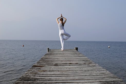 Italien, Gardasee, Frau (20-25) übt Yoga auf Steg - DKF00109