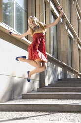 Vor Freude springende Frau im roten Kleid - MAEF00649